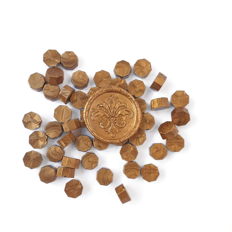 metallic antique gold sealing wax beads in a pile with wax seal on top