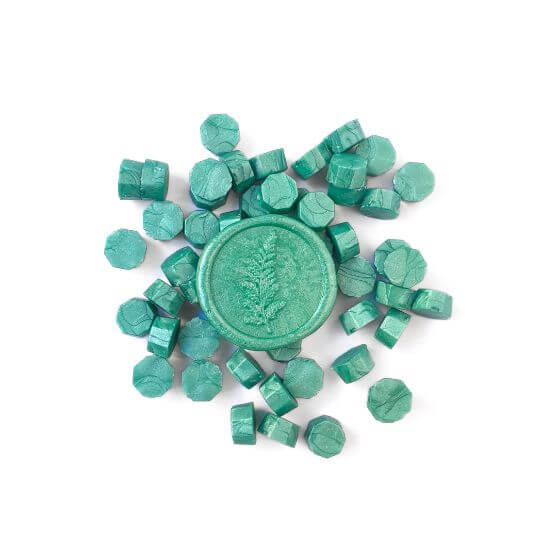 green sealing wax beads in a pile with a green fern leaf wax seal on top