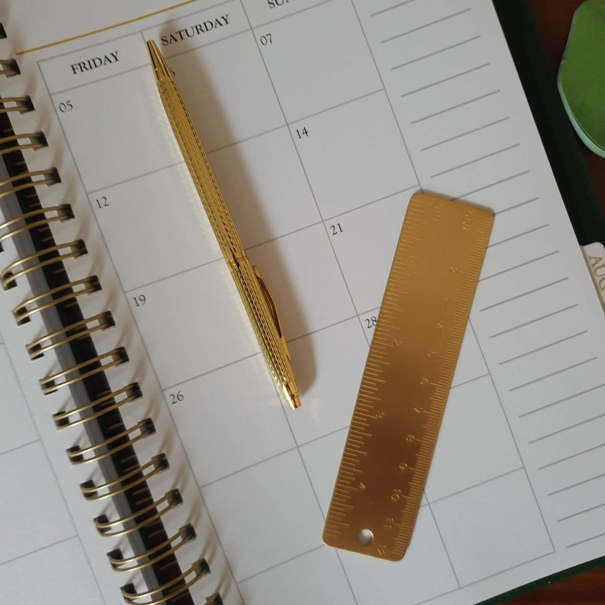 brass ruler on planner page with pen