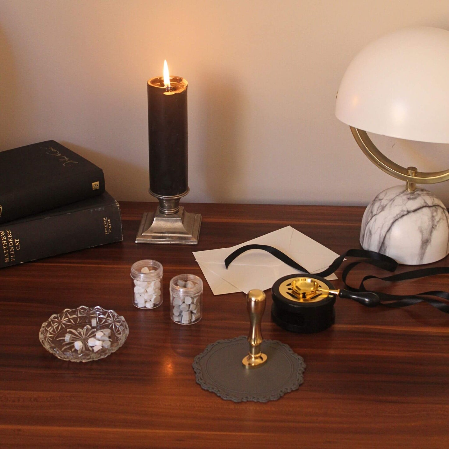 Brass wax seal kit and sealing wax on desk with candle and vintage books