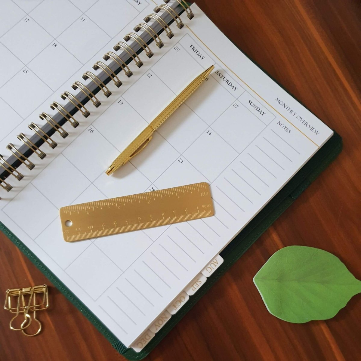 desk with planner open and brass ruler and pen on top