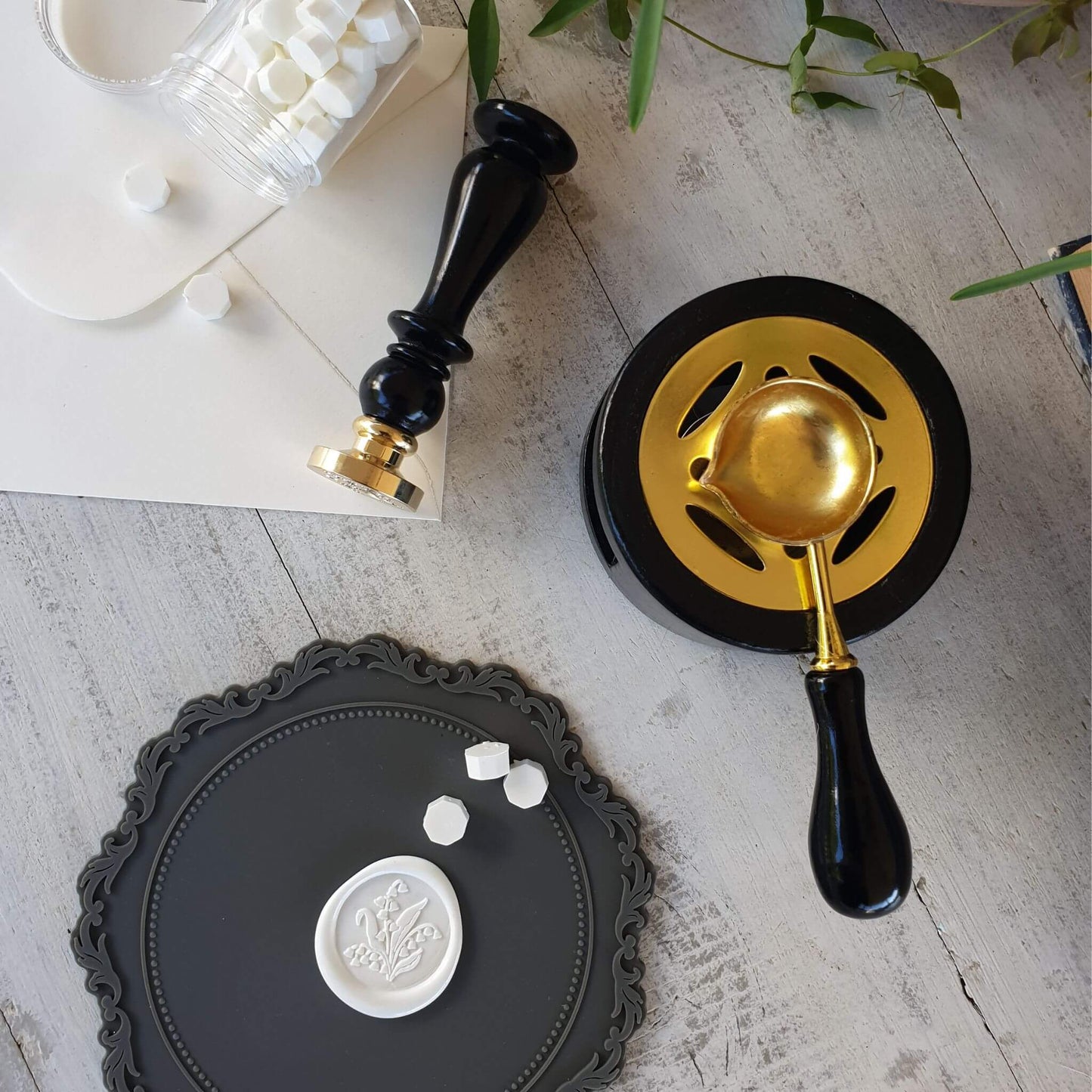 charcoal grey round wax sealing mat on thable with wax seal stamp, wax seal, wax melting stove and sealing wax beads