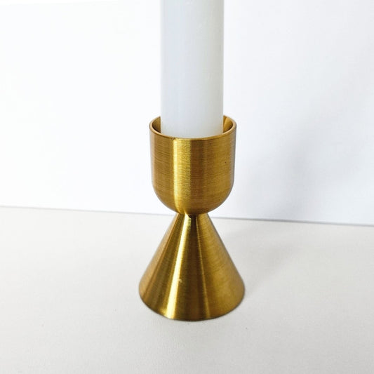 Gold candle holder with a white candle on a white background