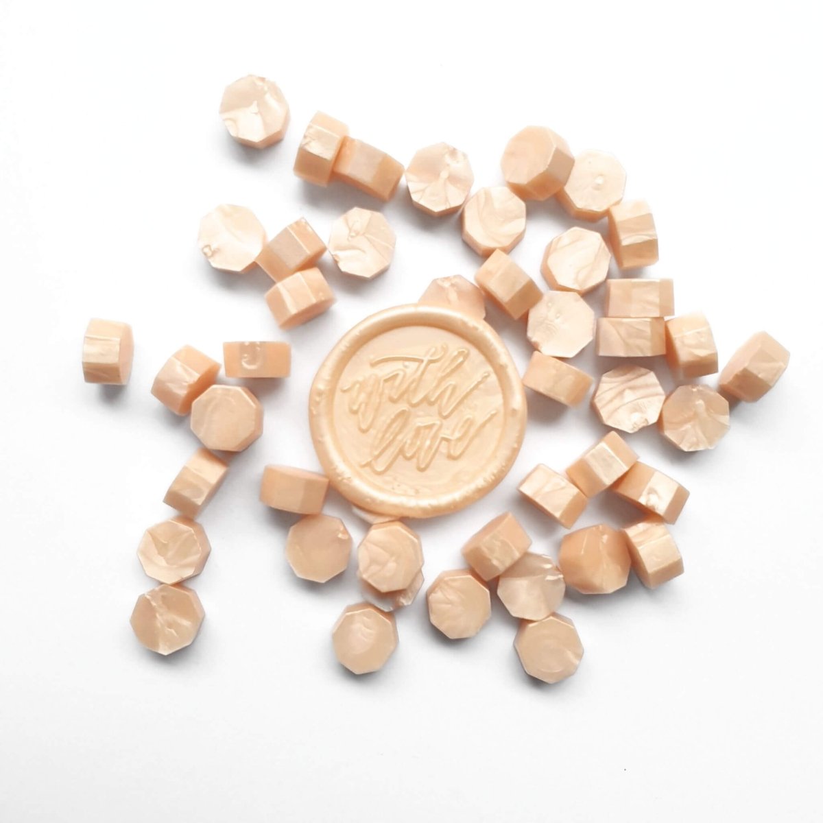 pastel apricot wax sealing beads with wax seal in center.