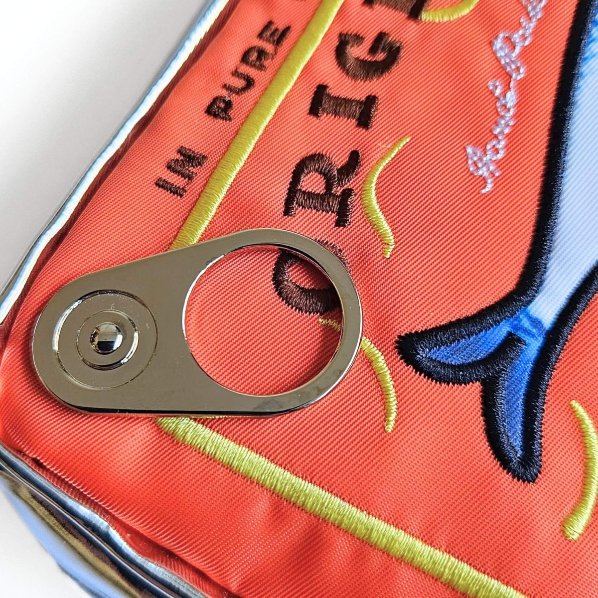 Close-up of an orange embroidered pencil case with ring pull on a white background