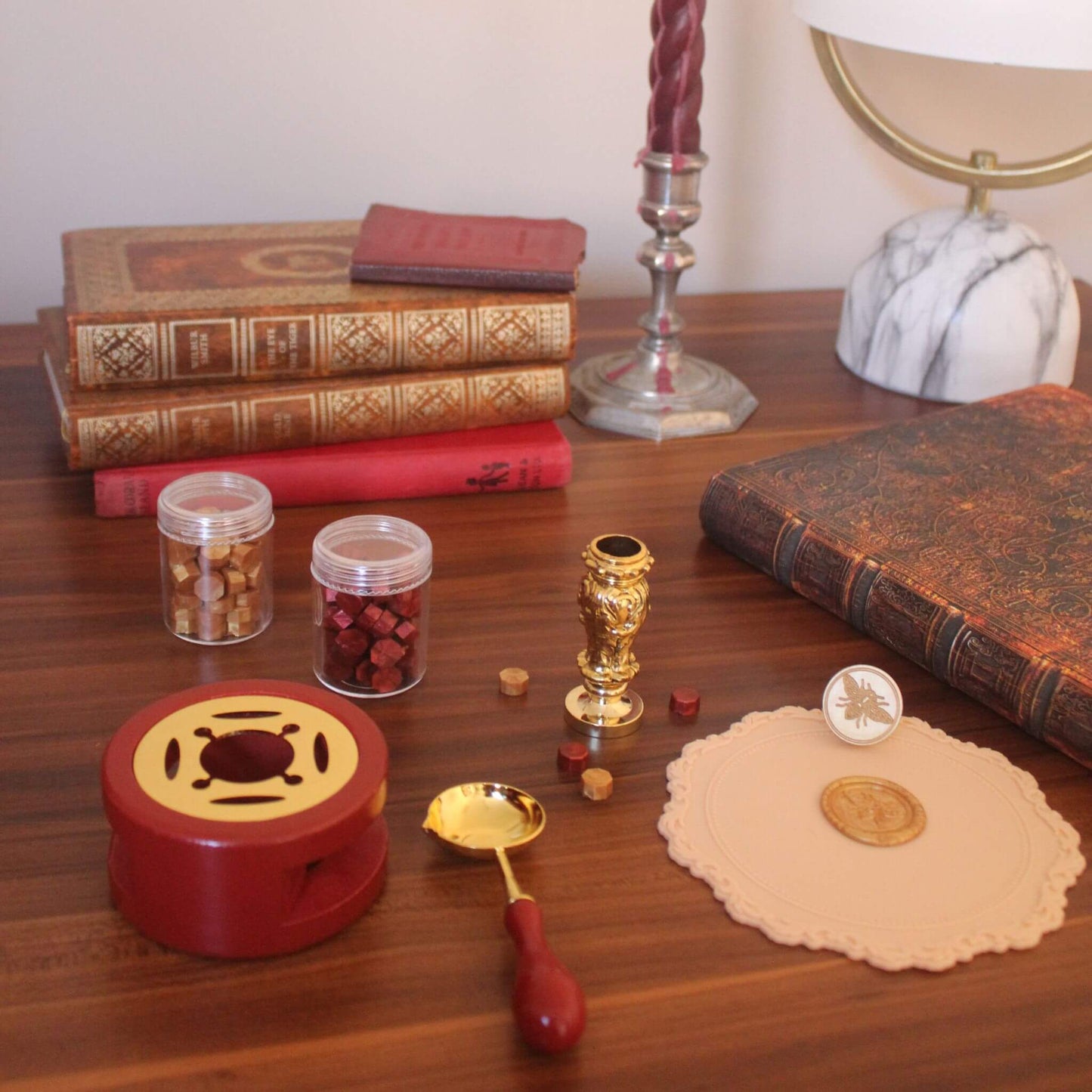 wax seal kit on wood desk with sealing wax and wax stamps next to pile of vintage books