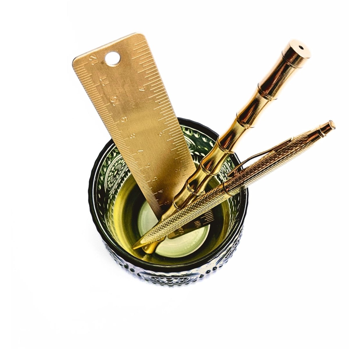 overhead view of green glass pen pot with pens inside