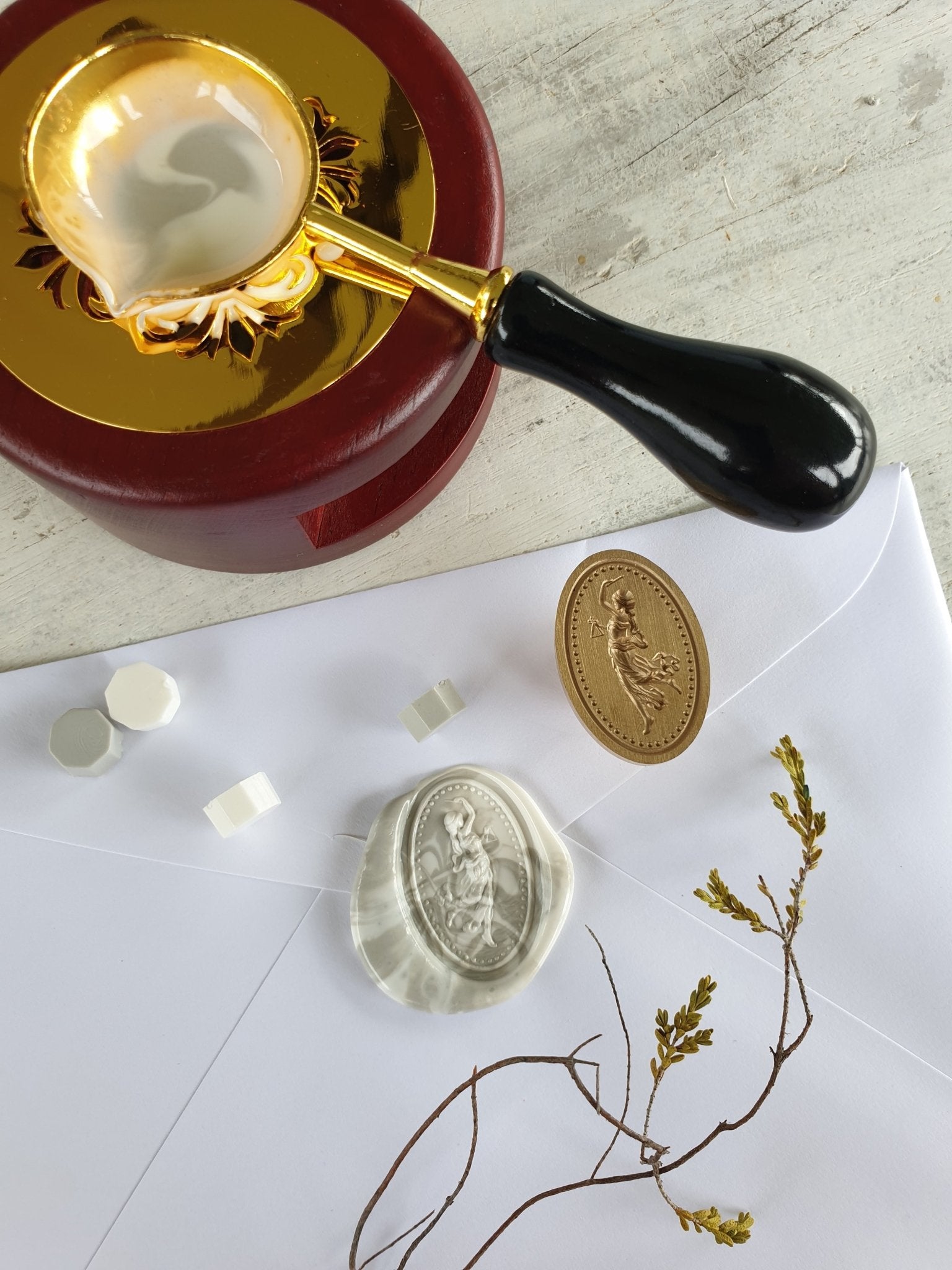 top view of goddess wax seal stamp next to wax seal and wax sealing tools