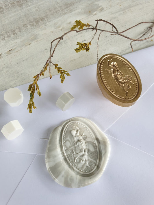 Goddess wax seal in brass next to marbled wax seal on envelope