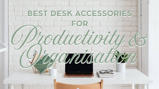 White desk in white office with laptop, potted plant and notebooks in gold tray