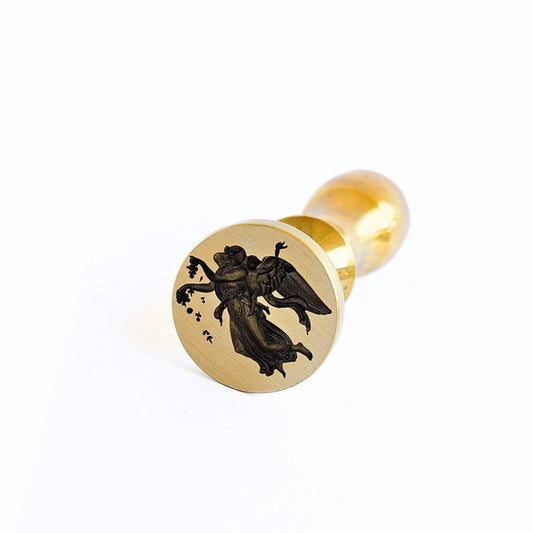 Gold wax seal stamp with an angel design on a white background