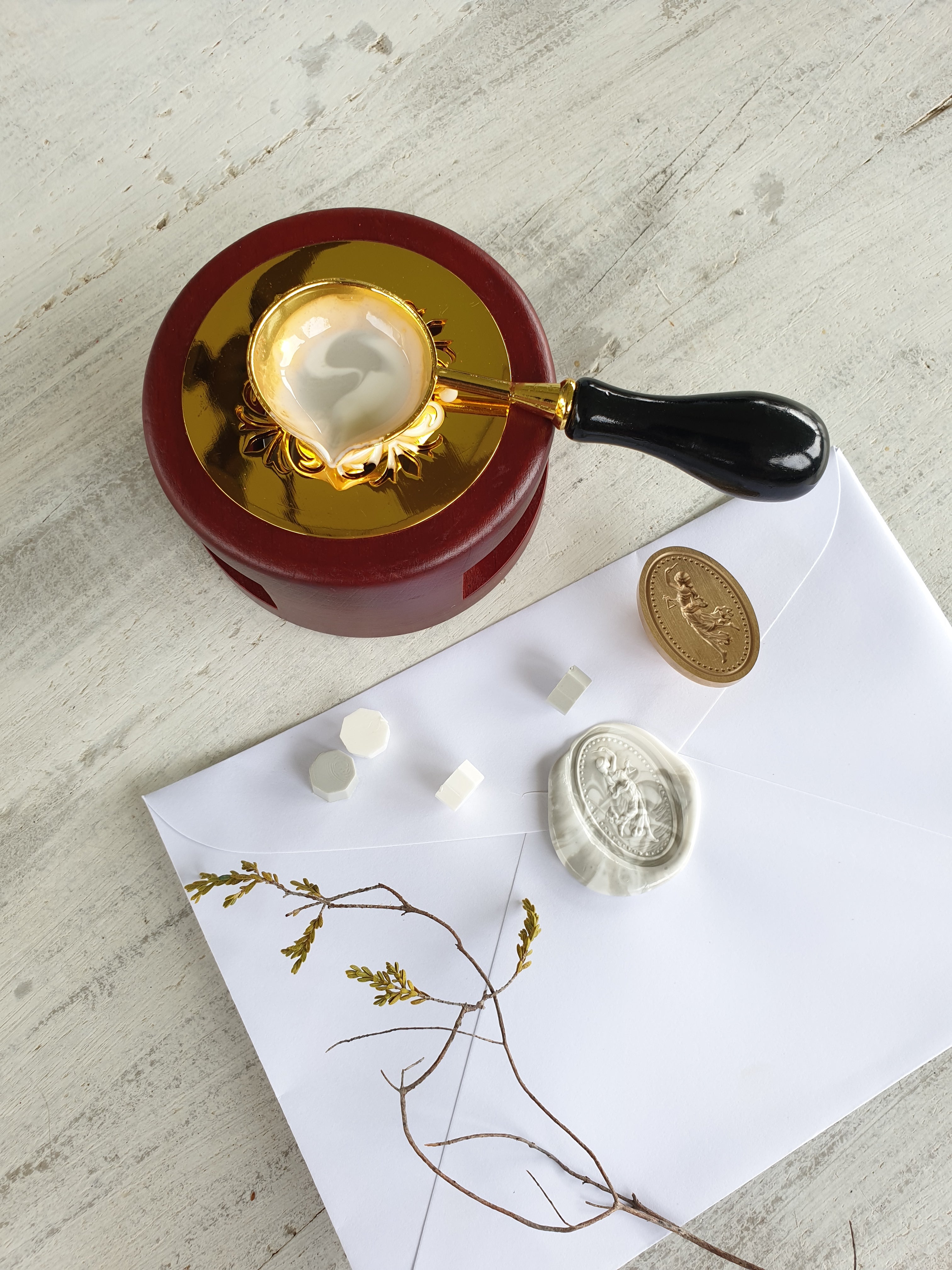 white envelope with grey and white marbled wax seal featuring roman goddess statue design and brass wax seal head with wax sealing beads