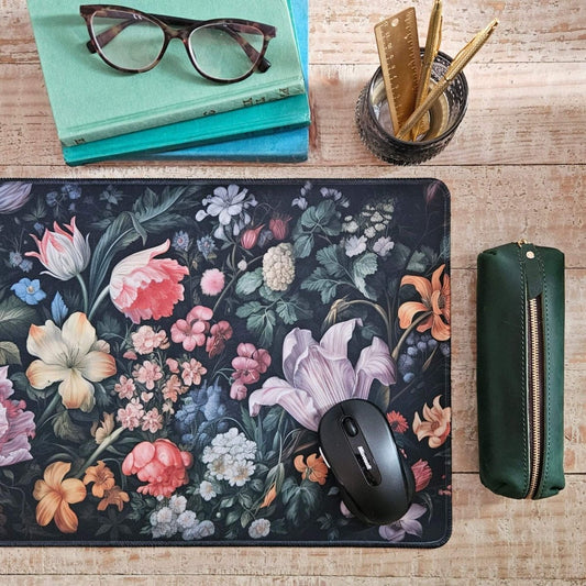 Floral mouse pad with a mouse, glasses on books, and stationery items on a wooden surface