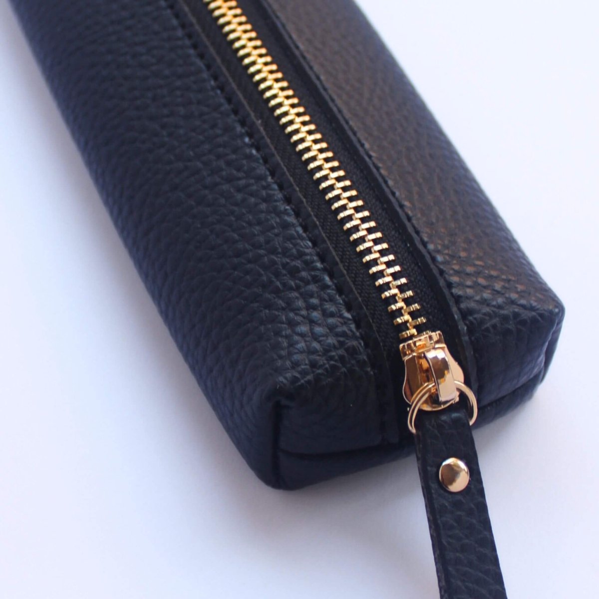 Close up of black vegan leather pencil case with gold zipper