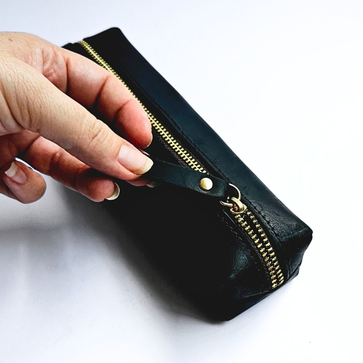 hand unzipping black pencil case