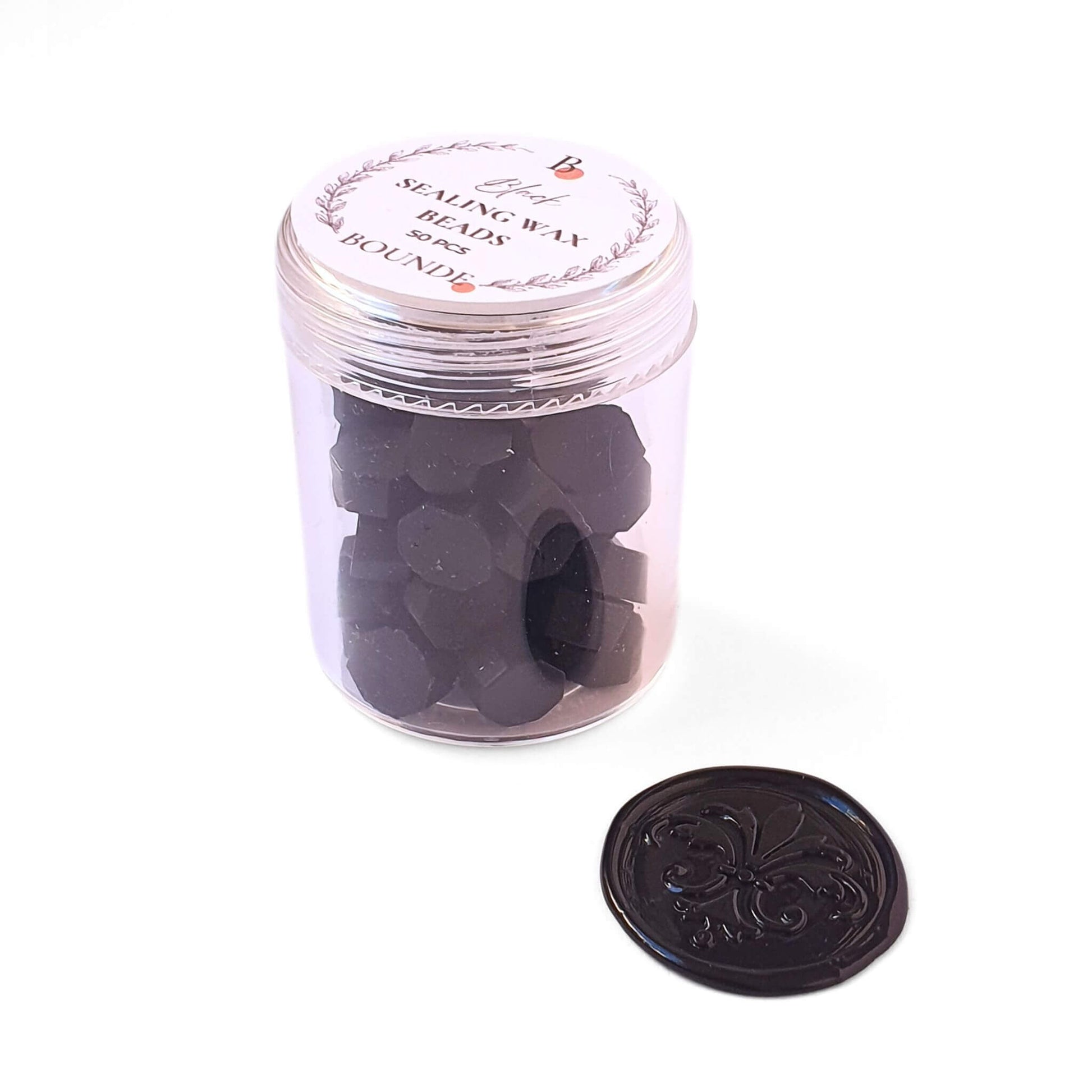 jar of black sealing wax beads and a black wax seal stamp next to it.