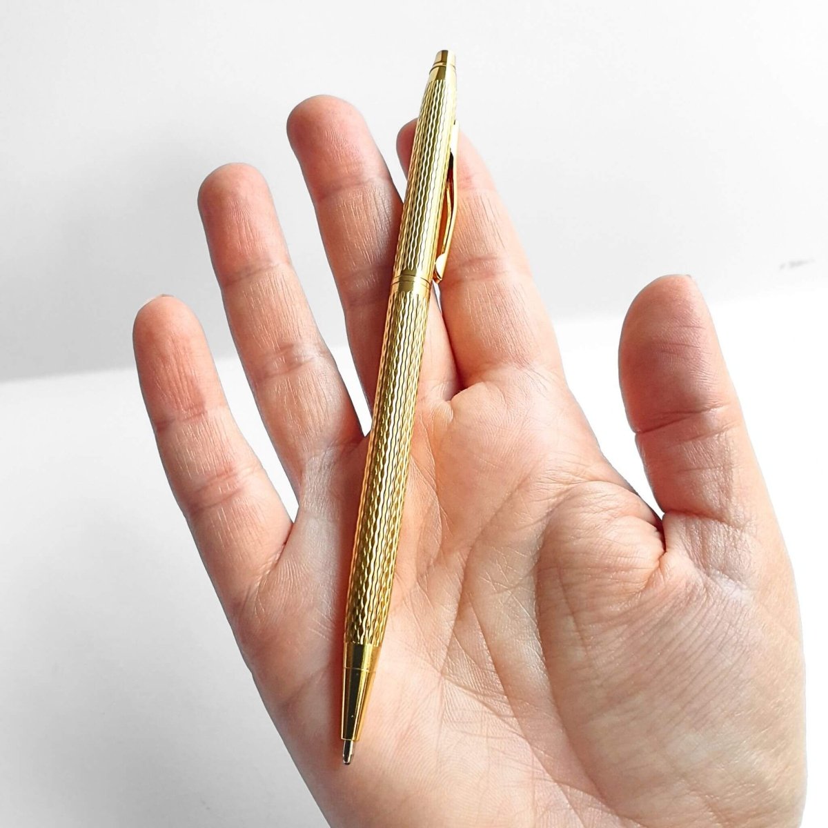 slim gold ballpoint pen held on palm