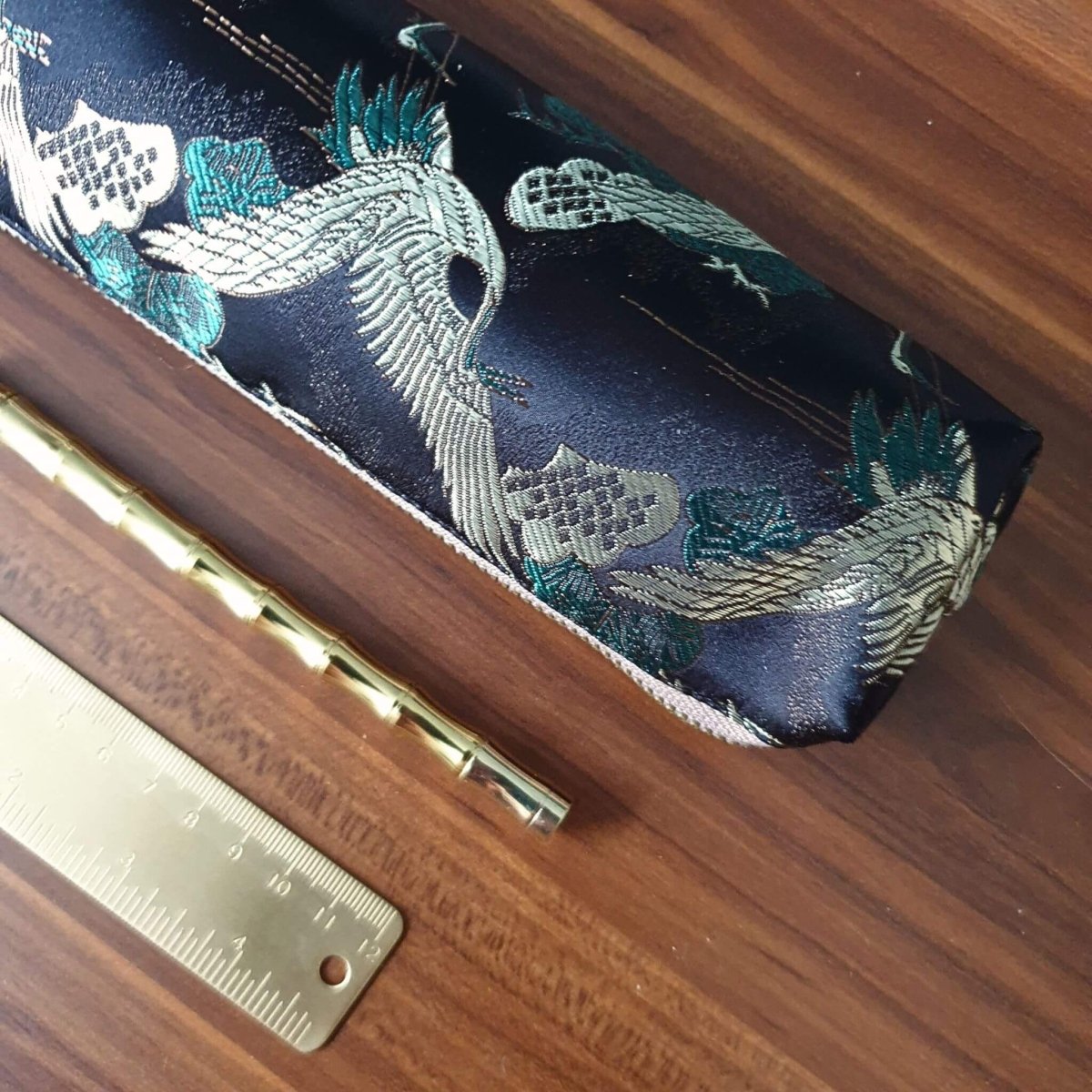 crane design pencil case with brass stationery on desk