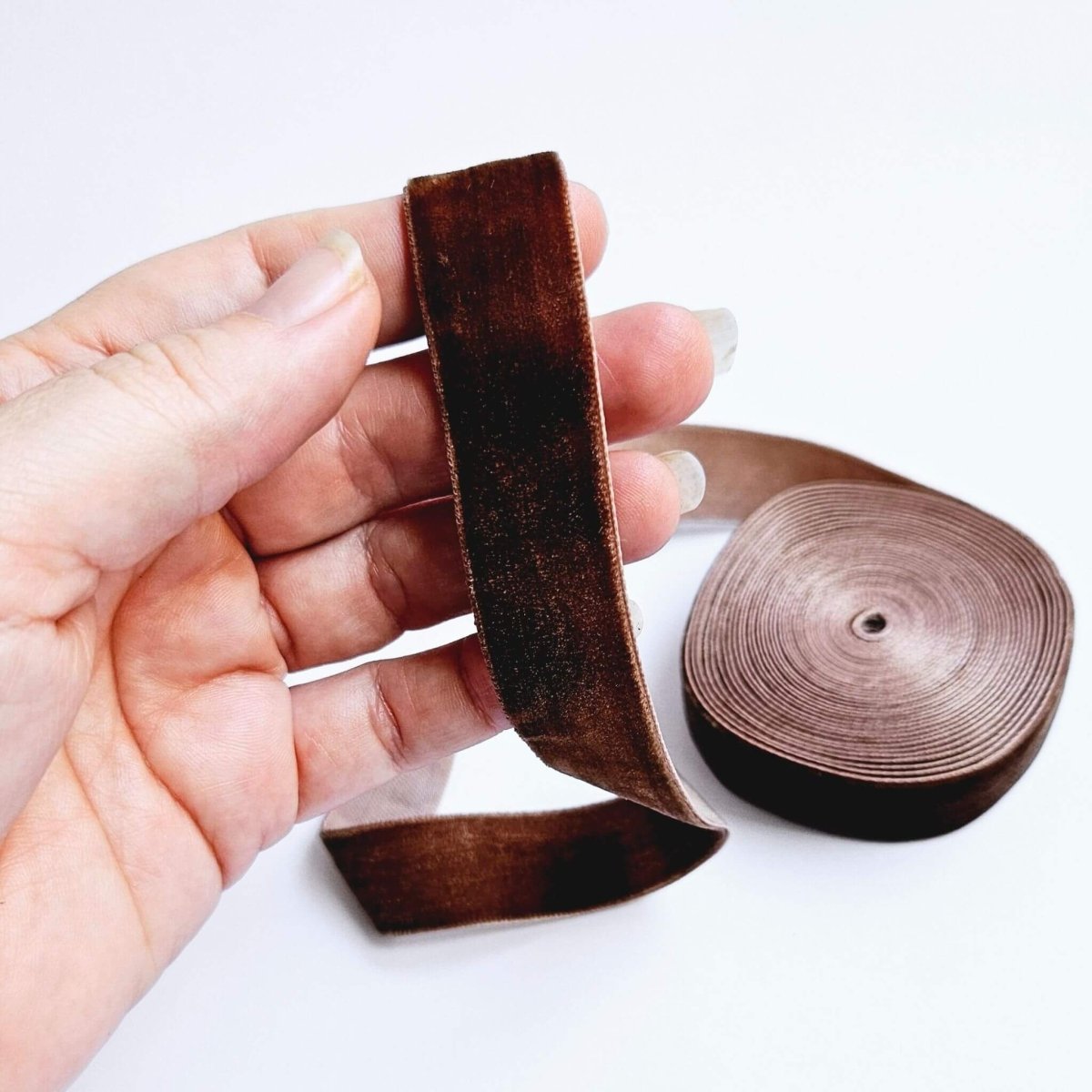 hand holding chocolate brown coloured ribbon