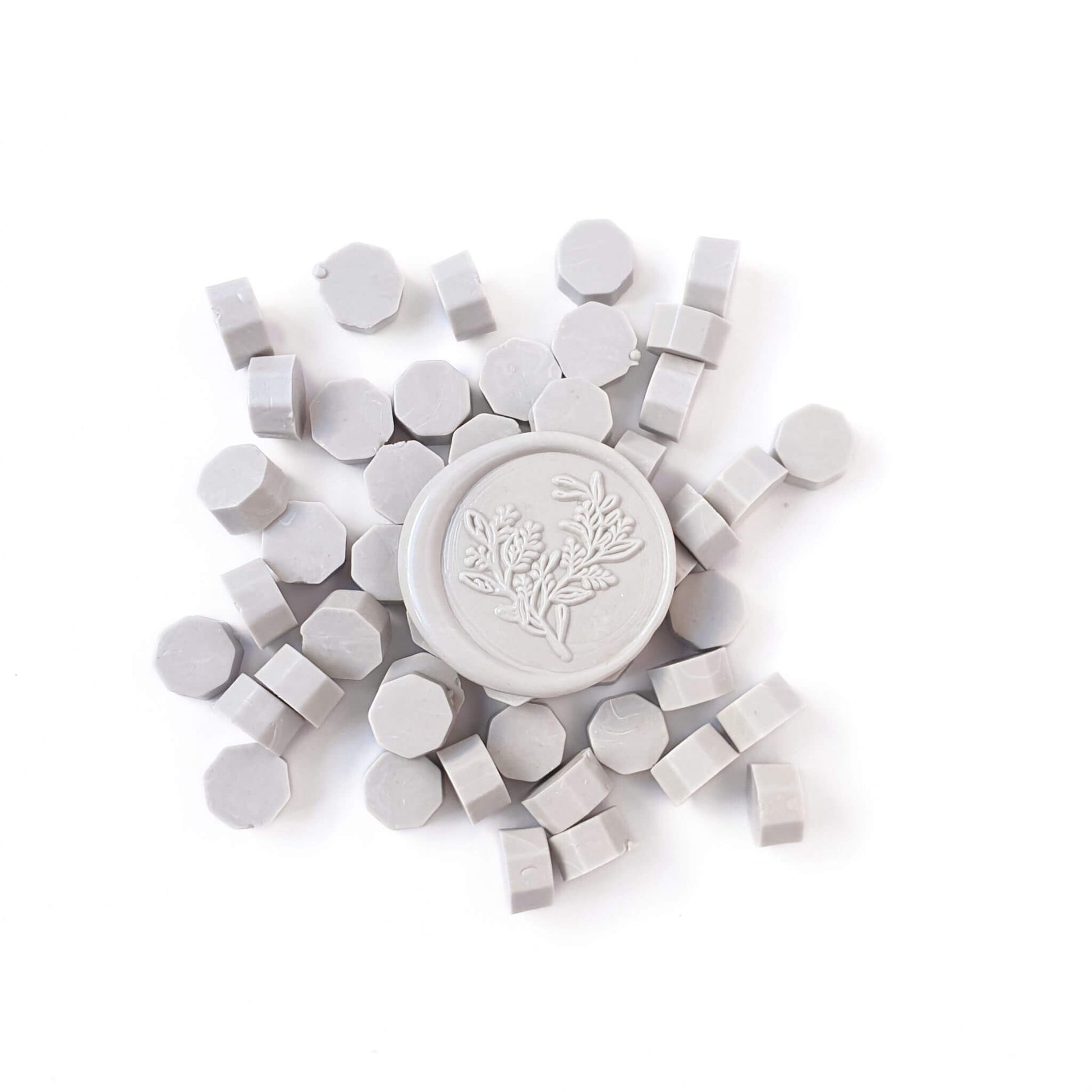 Dove grey wax sealing beads in a pile with a light grey wax seal in the middle
