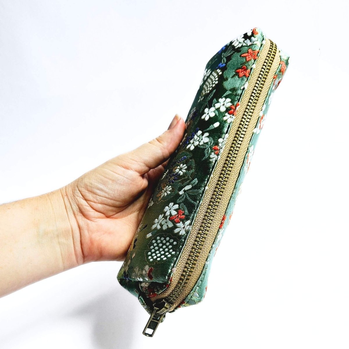 hand holding green floral makeup bag