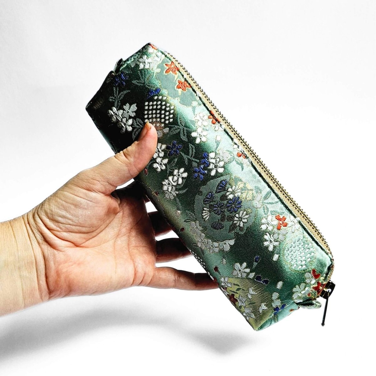 hand holding floral embroidered satin pencil case