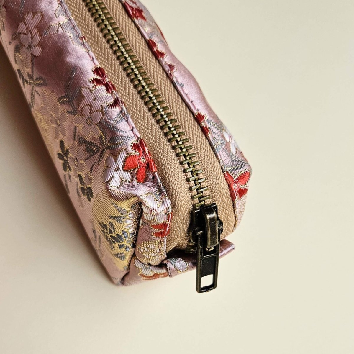 Floral-patterned fabric pouch with a zipper on a beige background