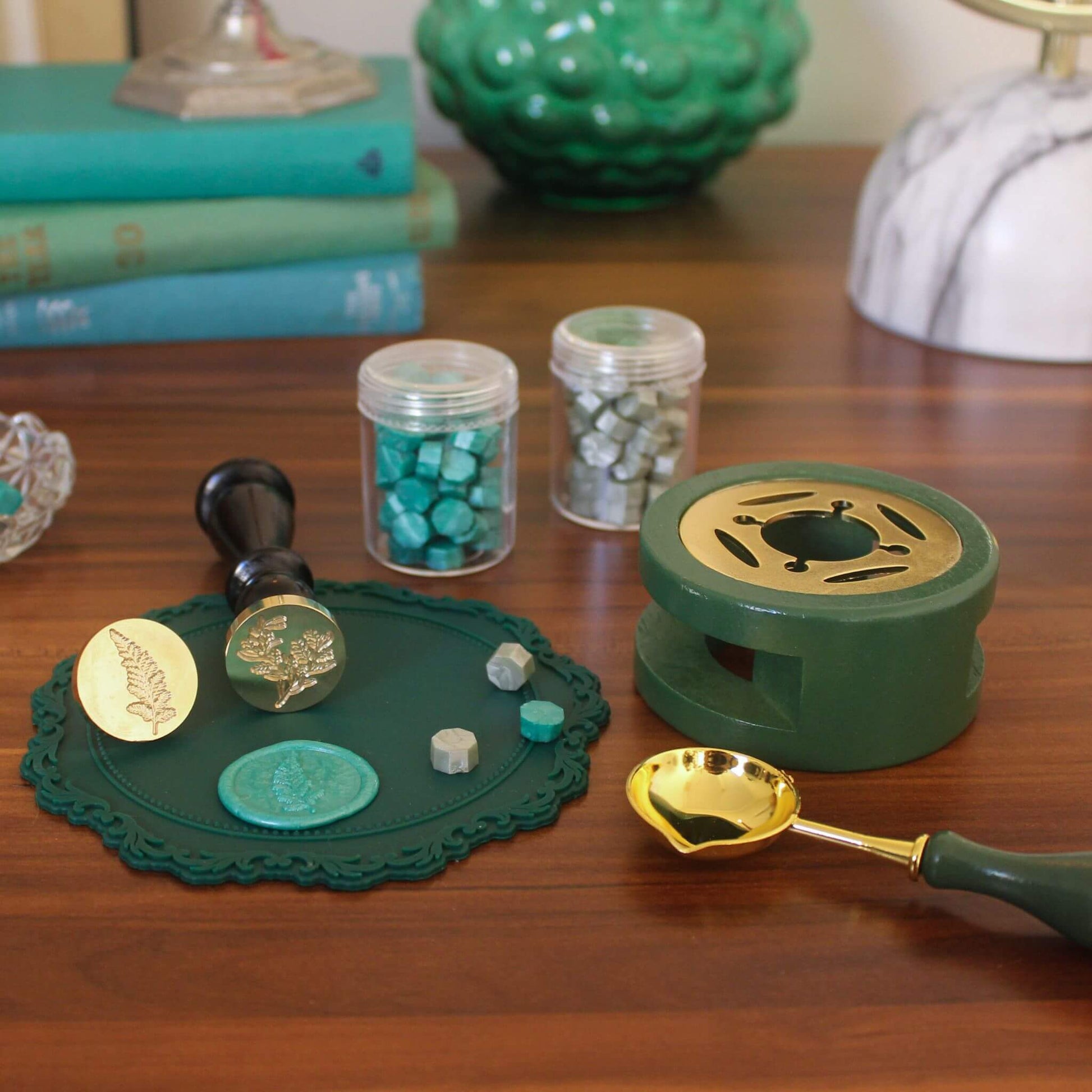 green wax seal kit on desk with wax seals and green sealing wax beads