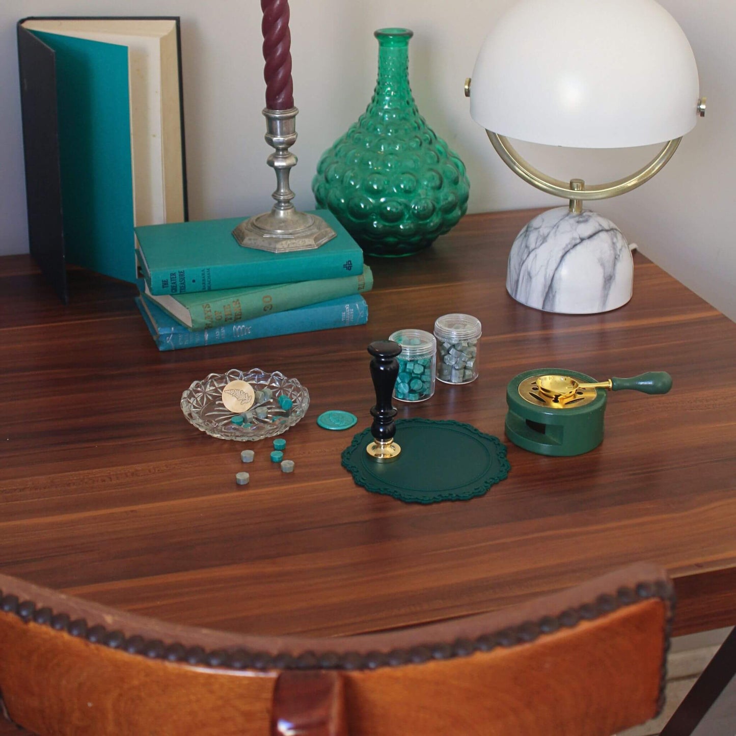 green lovers wax sealing kit laid out on wooden desk with vintage books and lamp