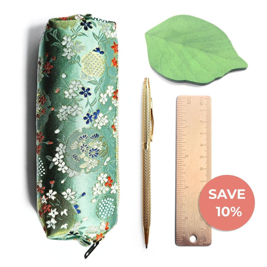 Green floral pencil case, gold pen, gold ruler and leaf shape sticky notes on white background