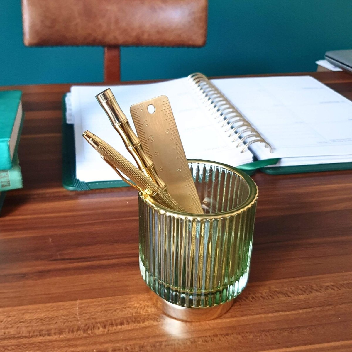 green glass pen holder on desk with planner