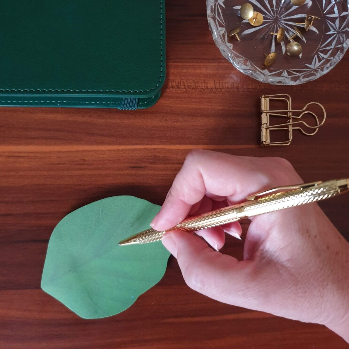 hand writing with gold pen at desk