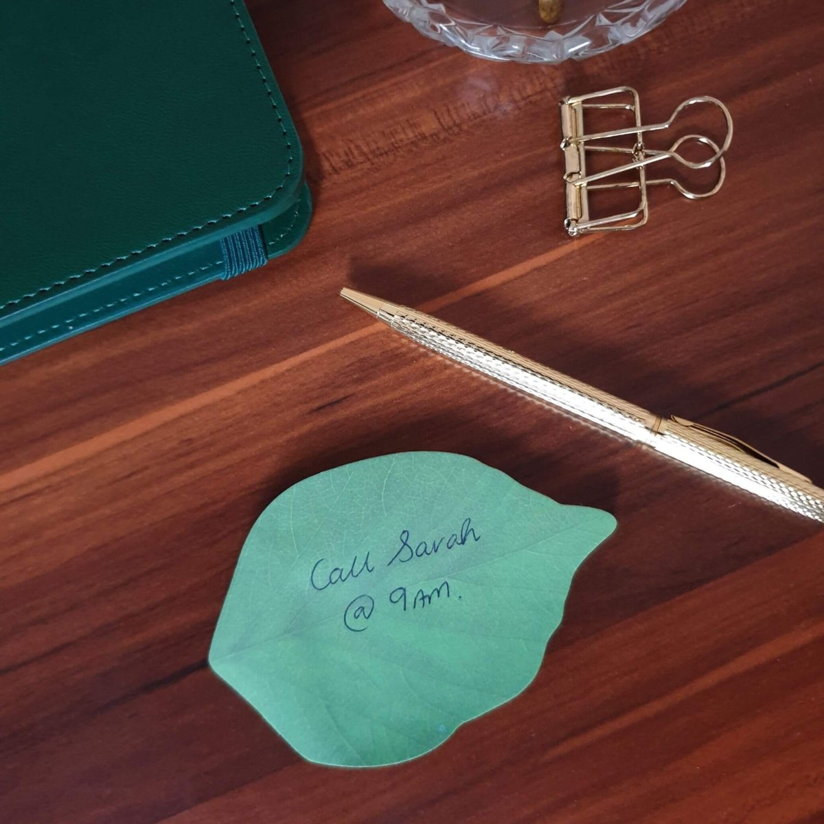 leaf shaped sticky notes on desk with pen and planner
