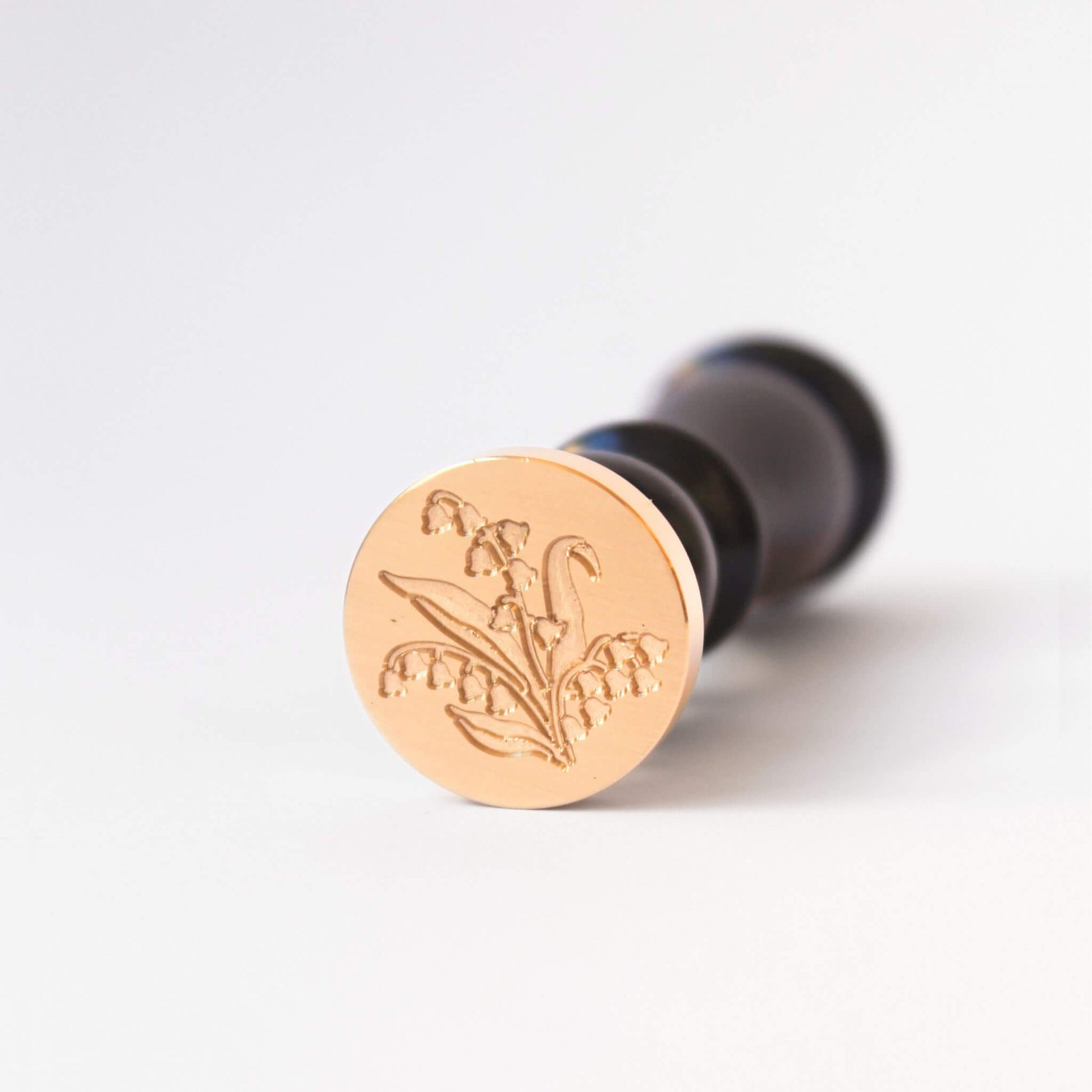 Brass wax seal head with engaving of Lily of the Valley flower and black wood wax seal stamp handle attached
