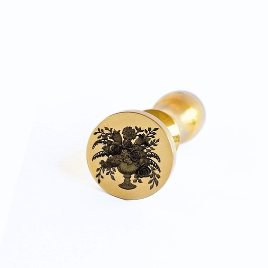 Gold wax seal stamp with floral design on a white background