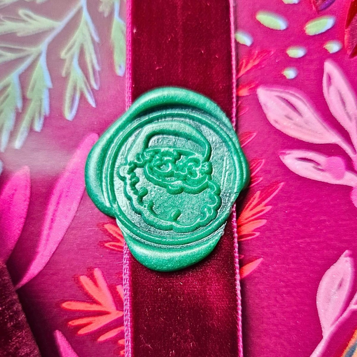 close up of santa wax seal in green on purple gift wrap