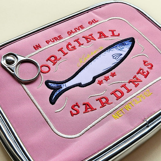 Pink pencil case with sardine label design on a beige background