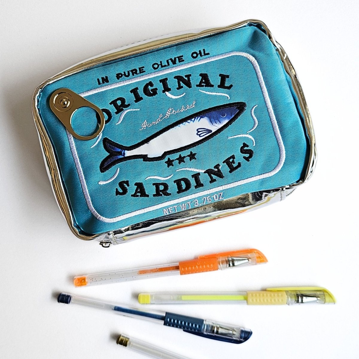 Sardine can-shaped case with pens on a white background