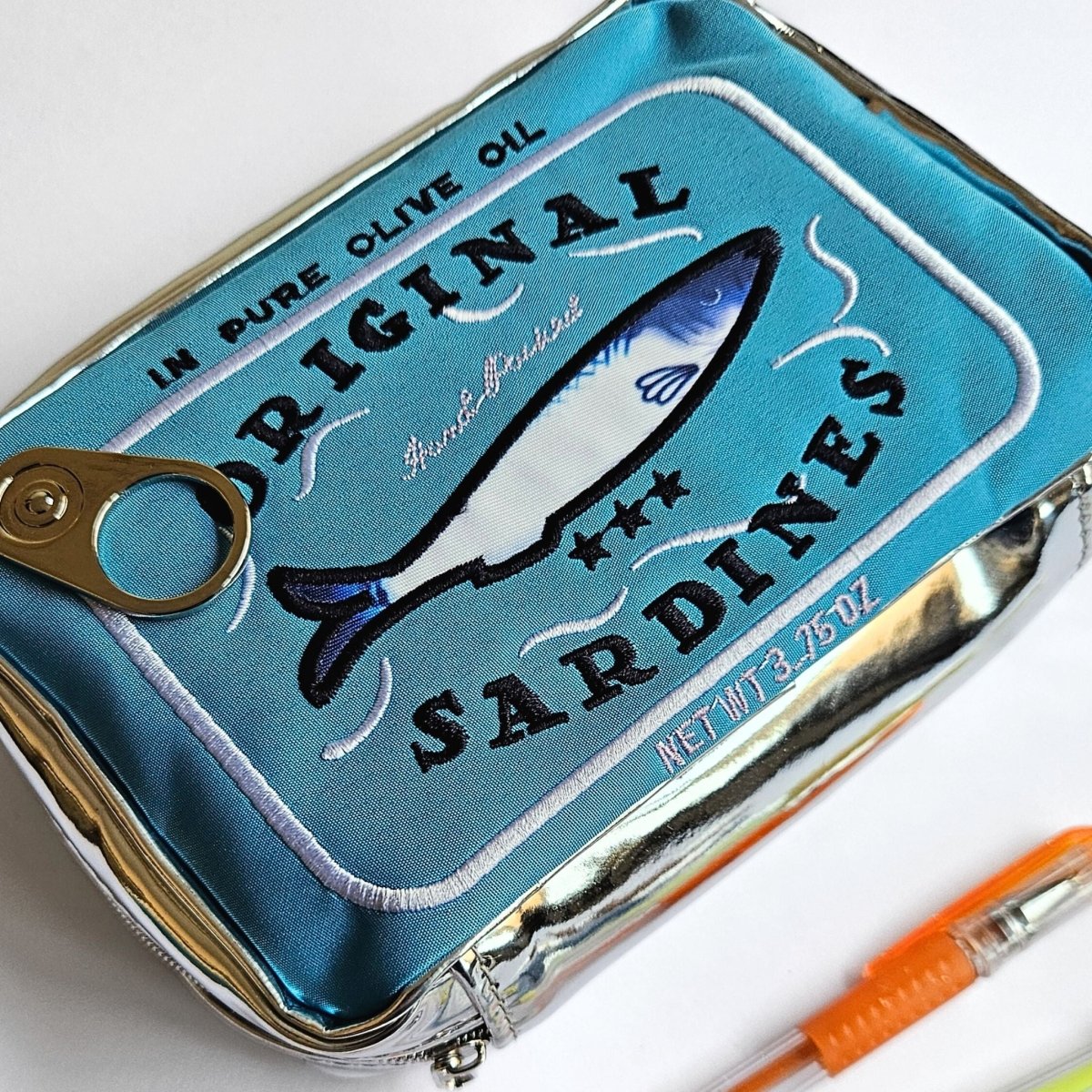 Sardine can-shaped pencil case with a fish illustration and 'Original Sardines' text on a white background.