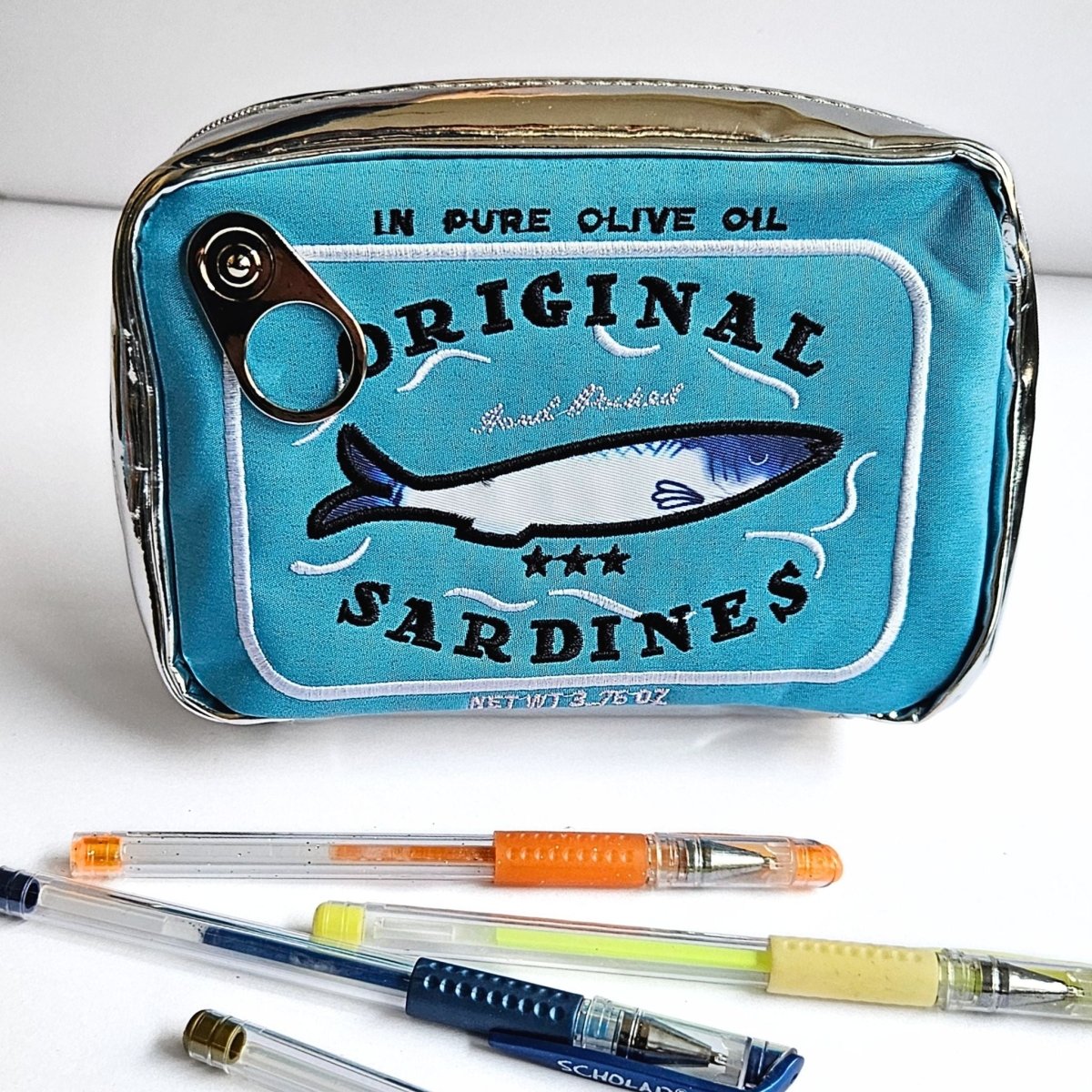 Blue pencil case with sardine can design and pens on a white background