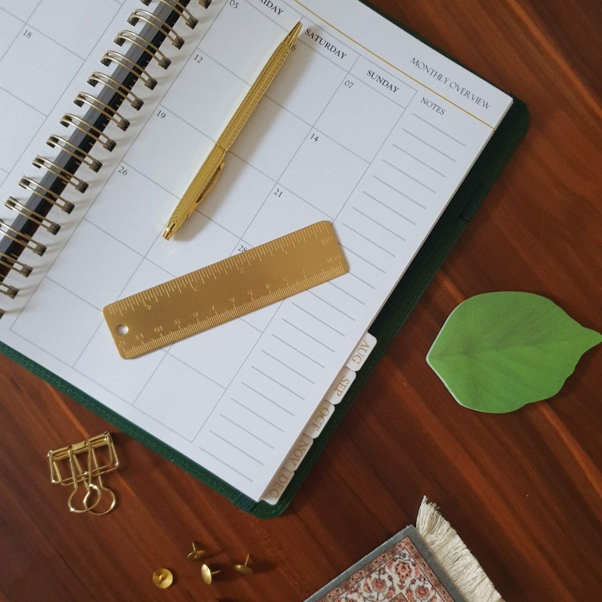 office desk with planner open and gold pen, ruler and clips