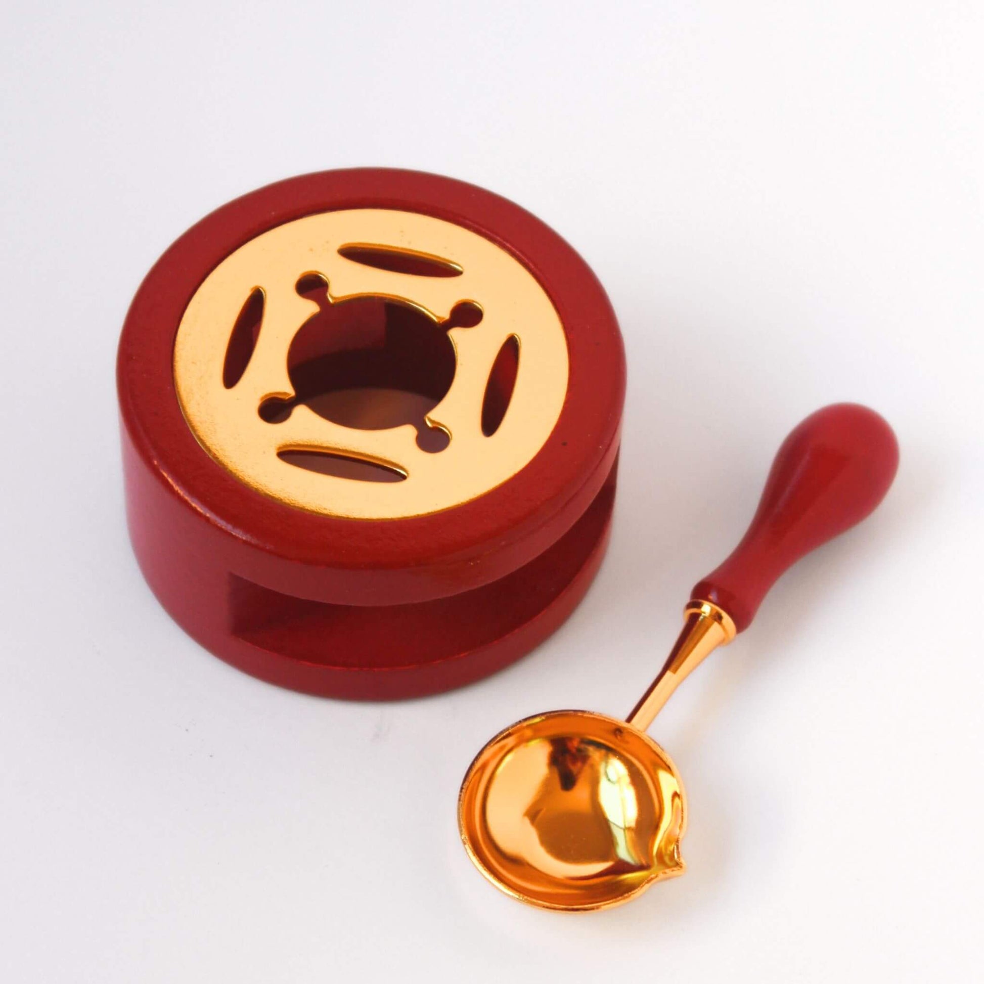 terracotta coloured wood and gold metal wax melting stove with matching spoon laid beside it