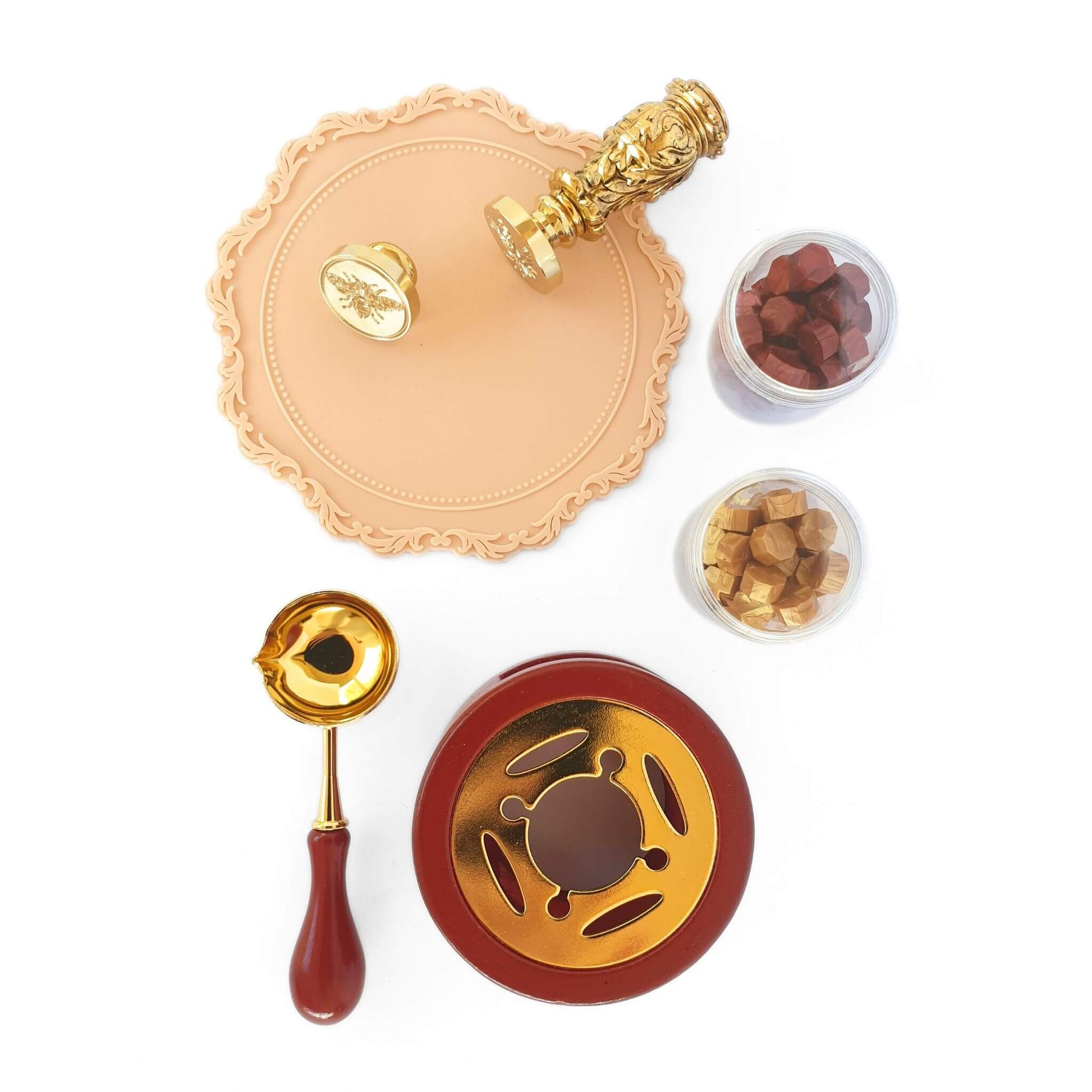 Tuscan Wax Seal Kit items in flatlay. Includes bee wax seal, rosemary wax seal head, tuscan wax seal handle in gold, gold and res sealing wax, terracotta wax melting stove and spoon
