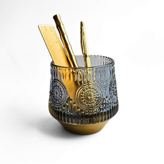 Decorative blue glass pen holder with gold accents on a white background