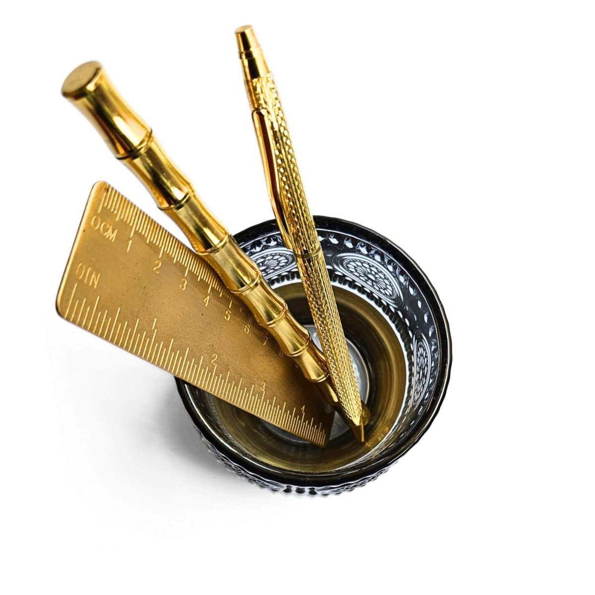 top view of blue glass pen holder with gold stationery inside.