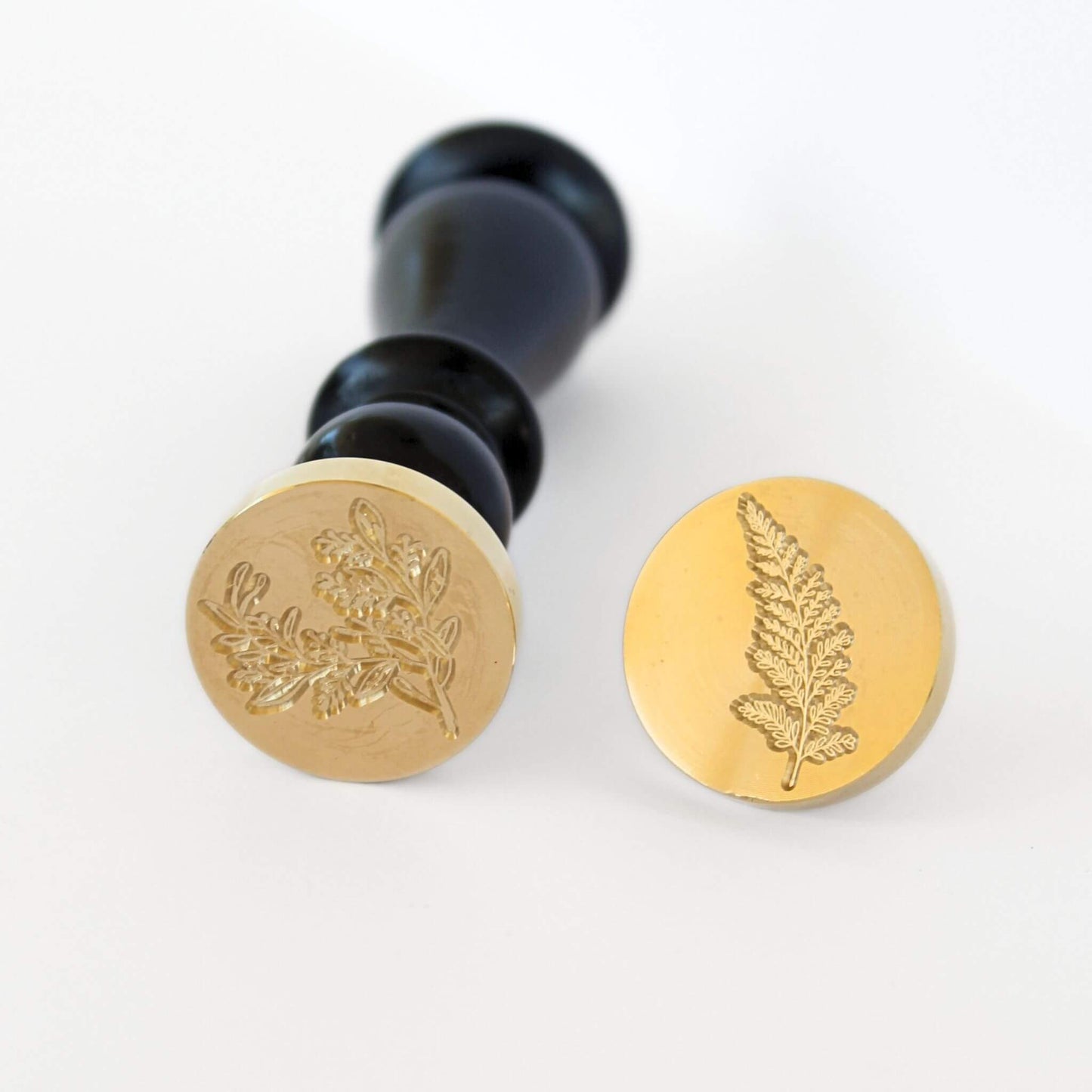 close up of fern and herboriste wax seal heads with black wooden handle