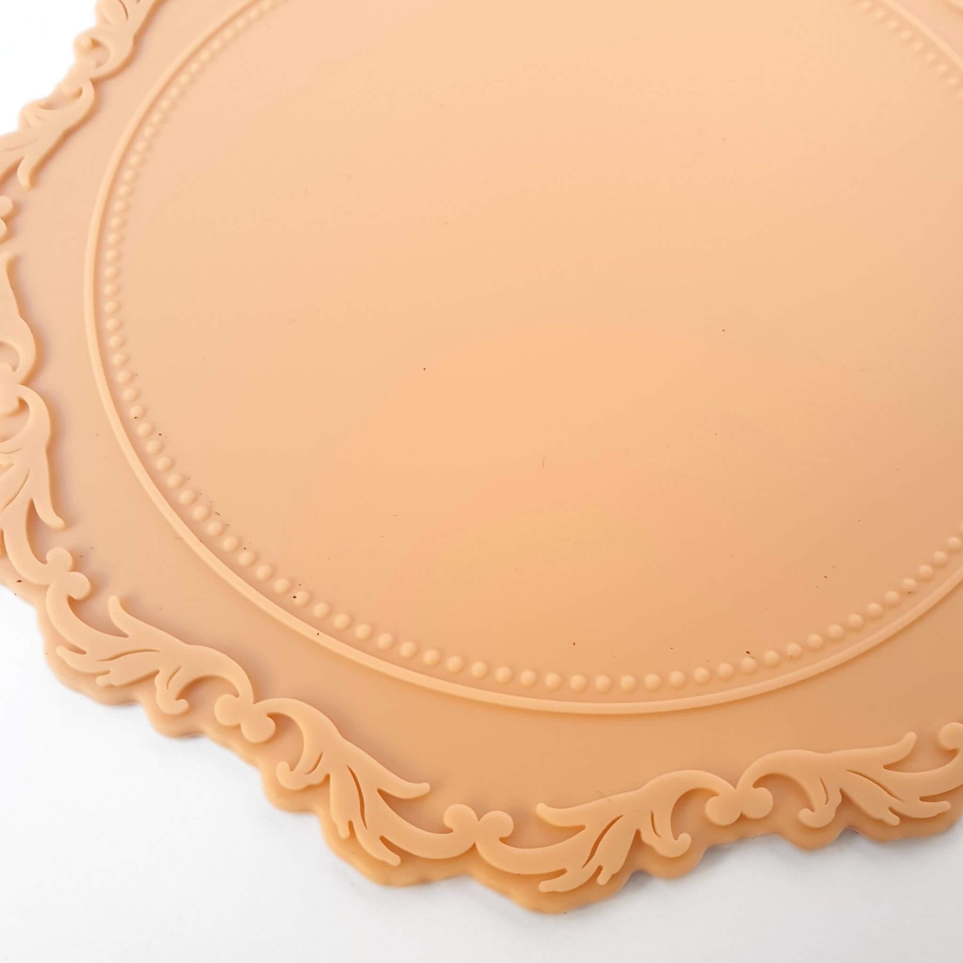 close up detail of peach coloured wax sealing mat with filigree edges