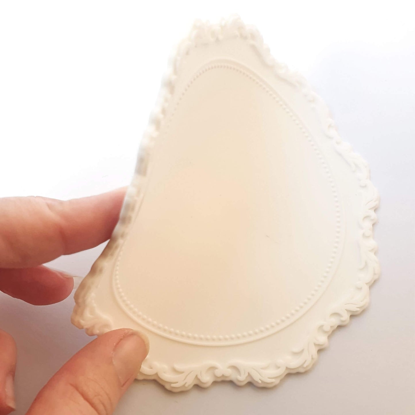 white vintage rococo style wax sealing mat being bent by hand to show fexibility