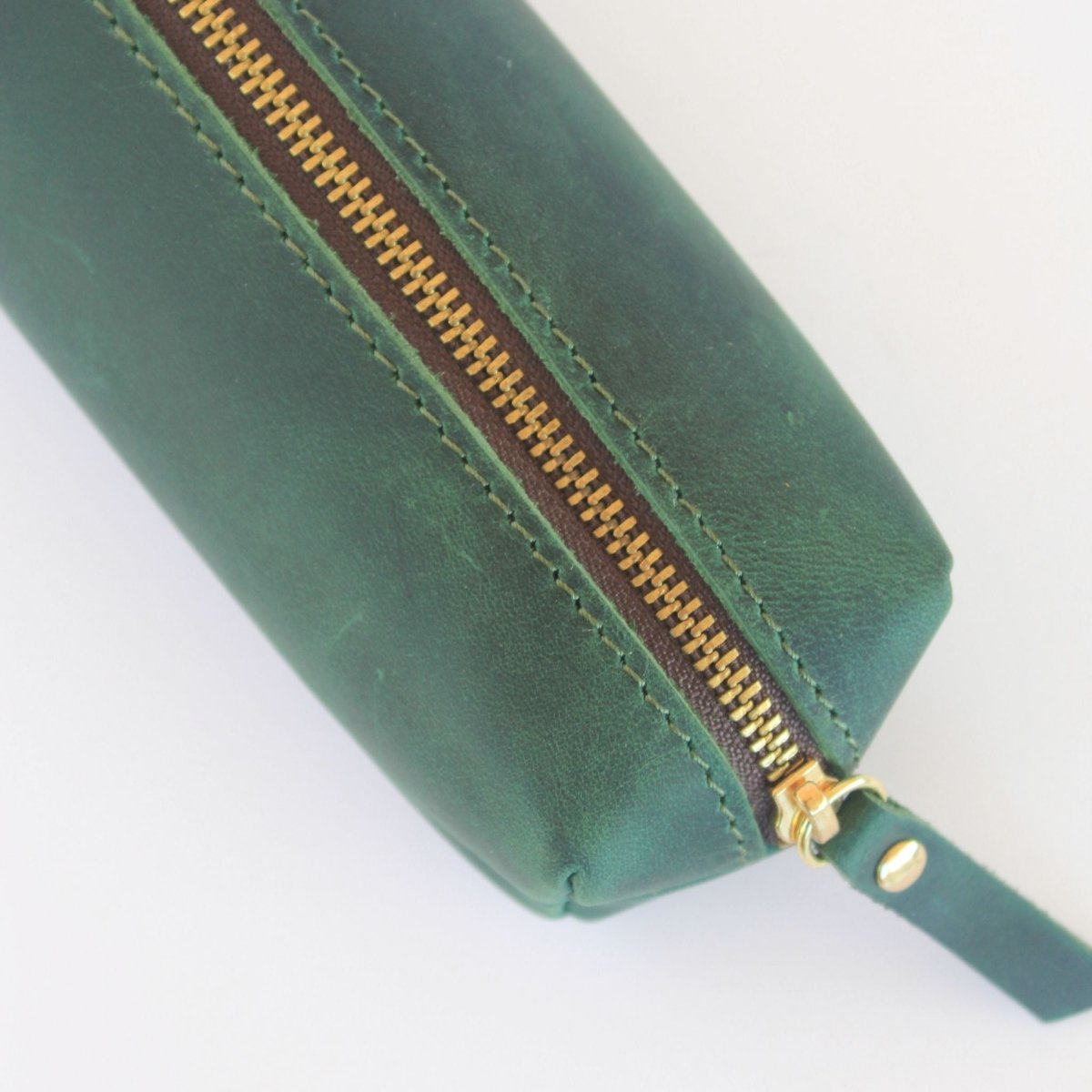 close up of full grain leather detail on green and gold pencil case